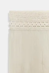 Pantalón de pierna ancha y tiro medio, confeccionado en tejido con textura arrugada. Presenta una cintura elástica destacada por un detalle de tejido en crochet a tono.