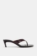 Sandalia tipo mule de piel color marrón oscuro, con diseño de tira entre los dedos y tacón fino de altura media.