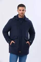 Saco de paño azul marino con capucha desmontable, cierre frontal oculto, bolsillos laterales con tapa y detalles en los puños.