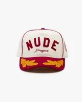 Gorra de béisbol de cinco paneles color blanca con visera color bordó. Presenta un parche frontal de fieltro con la inscripción "NUDE Project" y bordados de hojas en la visera en color amarillo mostaza.