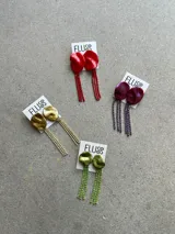 Caravanas colgantes de diseño irregular con base circular texturizada en tono dorado y flecos largos de strass brillantes.