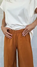 Pantalón de corte recto y tiro alto, con cintura elástica fruncida. Presenta un diseño fluido y minimalista.