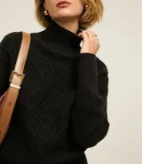 Suéter de manga larga confeccionado en tricot, con cuello alto y diseño de bordado de rombos en relieve. Presenta puños y ruedo acanalados.