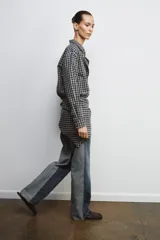 Jeans de tiro alto con diseño de paneles en contraste, combinando denim negro y gris. Presenta cinco bolsillos, cierre frontal con cremallera y botón metálico, y costuras con efecto deshilachado en la unión de los paneles.