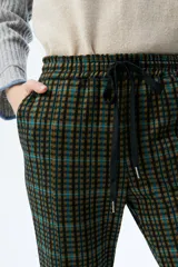 Pantalón acampanado a cuadros en tonos azul, marrón y negro, con cintura elástica y cordón ajustable.