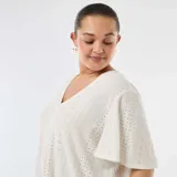 Camiseta blanca de manga corta con escote en V y diseño de tejido calado perforado.