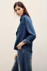 Camisa de denim gris oscuro efecto acid wash, de manga larga, con bolsillos frontales con solapa y broches metálicos a presión.