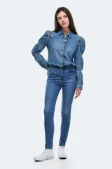 Jean ajustado (skinny) de tiro alto, color azul medio, con efecto levemente desgastado en la parte frontal de los muslos.