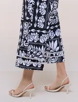 Pantalón crop ancho en color negro con estampado floral en contraste, bolsillos laterales y detalle de encaje en el ruedo.