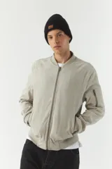 Campera bomber negra de simil gamuza, con cuello redondo, cierre frontal con cremallera, bolsillos laterales con cierre y puños elásticos.