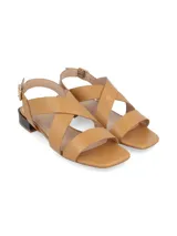 Sandalia de cuero color camel con tiras cruzadas en el empeine, cierre con hebilla lateral y taco bajo cuadrado en contraste color negro.