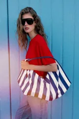Maxi bolsa de hombro con diseño de rayas horizontales en azul marino y blanco, asa superior integrada y cierre con botón imantado.