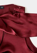 Blusa de satén color bordó con cuello drapeado y detalle de fular integrado que se sujeta en el hombro. Diseño sin mangas con tirantes anchos y corte recto.