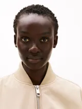 Campera bomber color beige, acolchada y repelente al agua, con cuello de béisbol, cierre frontal, puños y cuello de punto canalé, y dos bolsillos laterales ribeteados en diagonal.