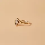 Anillo de diseño cruzado fabricado en plata 925 y oro, con una circonia central engastada y pequeños detalles de circonias laterales.