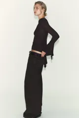 Camiseta de cuello redondo y manga larga, confeccionada en tejido rib con mezcla de lyocell. Presenta un diseño ajustado con terminación de volantes en los puños y bajo recto.