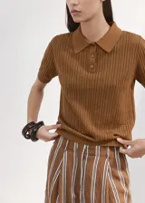 Chaleco de punto fino de algodón con diseño calado, cuello polo, manga corta y cierre frontal con tres botones.