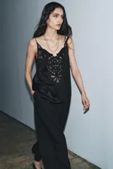 Top negro de viscosa con escote pico y tirantes finos. Presenta un aplique de encaje negro con diseño ornamental en el centro del pecho.