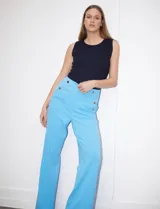 Pantalón naranja de crepe elastizado, corte recto, con bolsillos delanteros y apliques de botones metálicos.