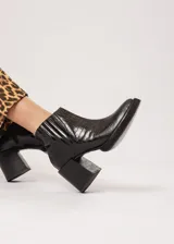 Botín negro de cuero con elástico lateral y cierre interno. Tiene plataforma delantera de 2 cm y taco de 8 cm.