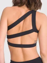 Top deportivo negro con tirantes elásticos cruzados en la espalda, soporte medio y almohadillas removibles.