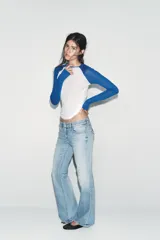 Camiseta de manga larga con cuerpo blanco y mangas raglán azules. Tiene cuello redondo y corte slim fit.