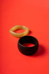 Set de dos brazaletes rígidos, uno de madera oscura con acabado mate y otro de resina en tono beige marmolado.