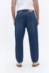 Pantalón de jean con corte baggy, tiro medio y diseño amplio en piernas y cadera. Cuenta con pasacintos y cierre frontal con botón.