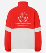 Campera deportiva de cuello alto con diseño color blocking en rojo y blanco. Presenta cierre frontal parcial, mangas largas con puños elásticos y bordado decorativo en el pecho. Confeccionada en poliamida con tecnología dry para mayor transpirabilidad.
