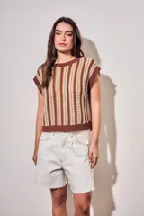 Chaleco de punto sin mangas con diseño de rayas verticales en tonos marrón, blanco y mostaza. Presenta cuello redondo y terminaciones acanaladas en color marrón sólido.