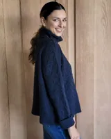 Sweater de lana color crudo con cuello alto y diseño trenzado.