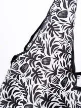 Bolsa de compras plegable con estampado botánico en blanco y negro, que incluye un gancho plástico para colgar.