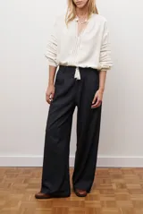 Pantalon de corte recto y pierna ancha, confeccionado en tejido tipo denim oscuro. Presenta tiro alto, cintura con cierre frontal y bolsillos laterales funcionales.