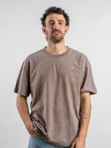 Remera oversize de algodón color negro con efecto lavado. Presenta un estampado gráfico en la espalda con la frase 'Freeze the moment' y un diseño de cámara fotográfica en tonos rojizos.