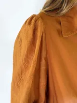 Vestido camisero largo de color naranja, con mangas largas abullonadas y cierre frontal de botones.