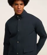 Campera bomber azul marino para hombre, confeccionada en sarga de algodón sostenible. Tiene cuello alto, cierre abotonado, bolsillos cargo con solapa y puños elásticos.