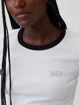 Remera corta de ajuste ceñido color blanco con cuello redondo y ribete negro. Presenta mangas cortas y el logo bordado de Gap en el pecho.