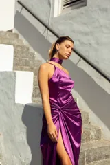 Vestido midi de satén color violeta, con escote asimétrico, falda con abertura lateral y detalle drapeado en la cintura. Incluye un cuello tipo choker que se puede usar de diferentes formas.