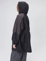 Campera tipo piloto con capucha, cierre frontal con botones y detalle de costuras en zigzag. Presenta cordones ajustables en la cintura y capucha, puños elásticos y logo bordado en el pecho.