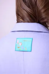 Tapado de lana color fucsia, con solapas clásicas, cierre frontal de dos botones y bolsillos laterales amplios. Diseño de corte recto y largo medio.