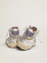 Zapatilla de caña media inspirada en el estilo skate de los ochenta, confeccionada en cuero vacuno plateado con efecto envejecido, estrella lateral y detalles en gamuza beige. Incorpora perforaciones de estilo inglés, cordones blancos con logotipo y suela de goma con acabado desgastado.