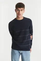 Sweater de punto grueso color azul marino con rayas horizontales finas en color gris claro. Cuello redondo y calce holgado.