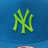 Gorro New Era 9FIFTY Under Scape turquesa con logo de los New York Yankees bordado en verde flúor.