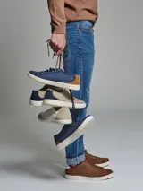 Zapatillas acordonadas de cuero nobuck color marrón con diseño calado y suela blanca de goma.