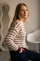 Sweater de tejido de punto con diseño a rayas horizontales en color crema y bordó, de corte holgado, cuello redondo y puños acanalados.