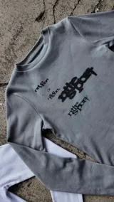 Remera de manga larga gris melange de tejido acanalado con diseño de estampado tipográfico en negro en el frente.