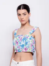 Top blanco con estampado floral en tonos naranja y lila, de corte cropped y breteles anchos.