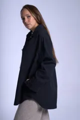 Sobrecamisa color beige confeccionada en gabardina, de corte holgado, con cuello camisero, cierre frontal con botones, dos bolsillos de parche en el pecho y mangas largas con puños abotonados.