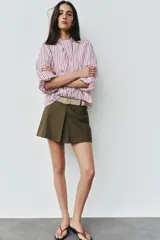 Falda pantalón de tiro medio en color verde militar, con diseño de pliegue delantero y cierre lateral con cremallera oculta. Incluye un cinturón ancho en tono tostado con hebilla metálica ovalada.