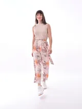 Pantalón babucha de tiro alto con cintura fruncida y lazo para ajustar. Estampado de hojas tropicales en tonos naranja y marrón sobre fondo blanco.